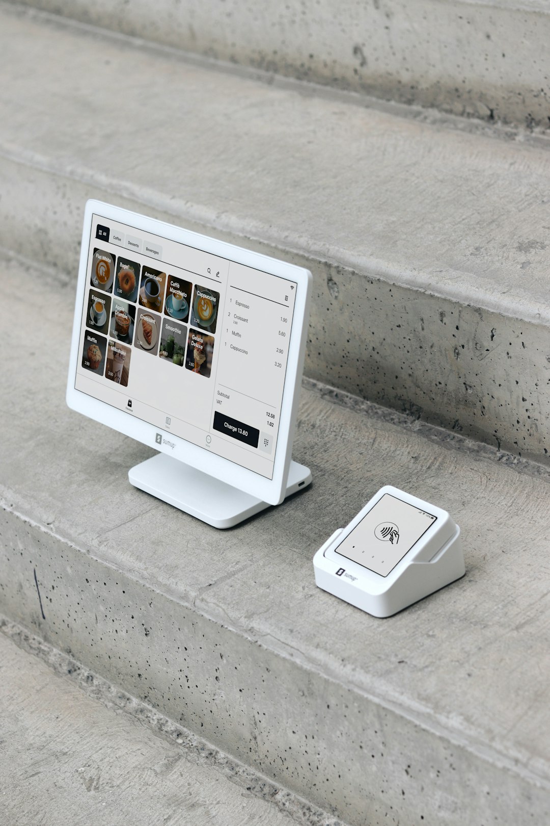 home-services-02 A point of sale (POS) setup is displayed on concrete steps, featuring a modern white display screen alongside a compact card reader. The screen shows a digital menu with various products, while the card reader is ready for contactless payments. This clean, minimalistic setup highlights the portability and sleek design of SumUp’s payment solutions, ideal for small businesses, cafes, and retail environments that value both functionality and aesthetics.